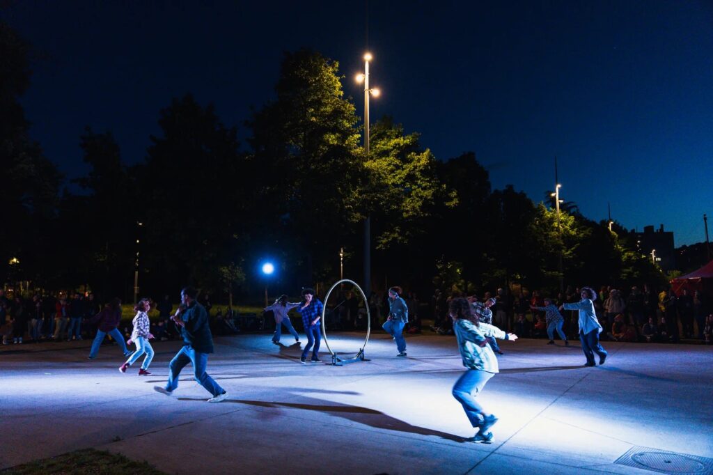 Vue de personnes en train de danser sur une place publique, de nuit